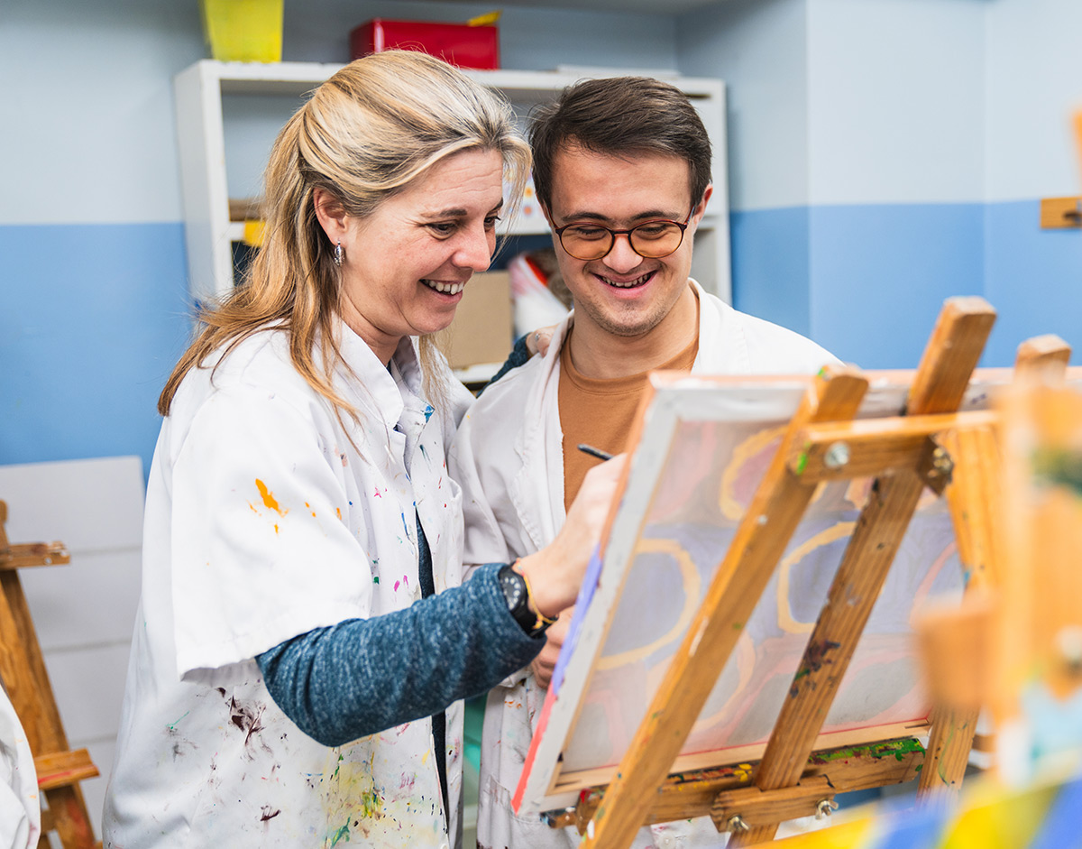 A teacher and ABA student painting a picture